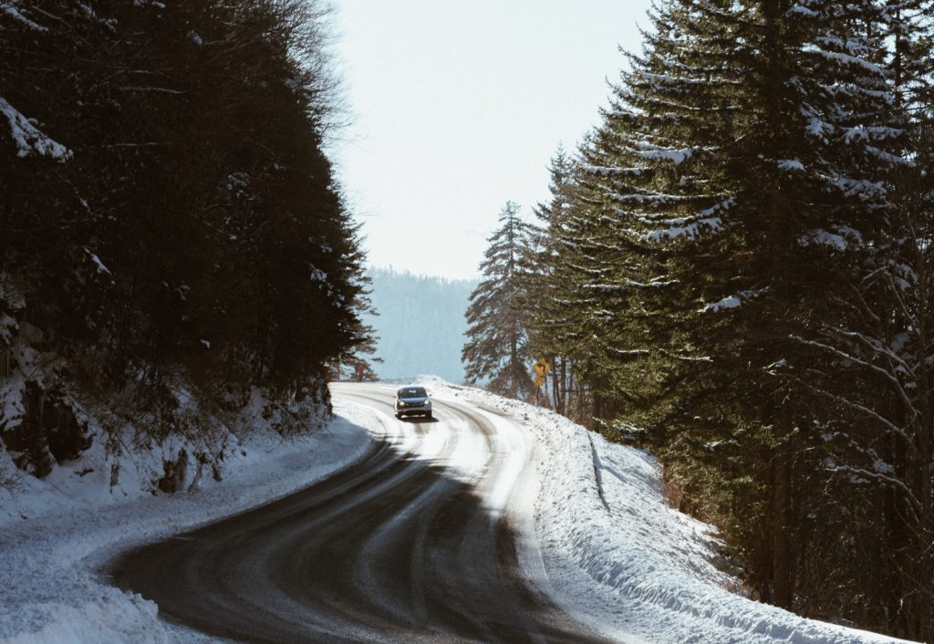 car driving on winter roads in heavily treed mountains